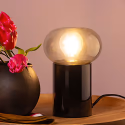 La lampe de table Knut allie design contemporain et élégance. Sa structure en métal noir et son abat-jour en verre fumé lui c ...